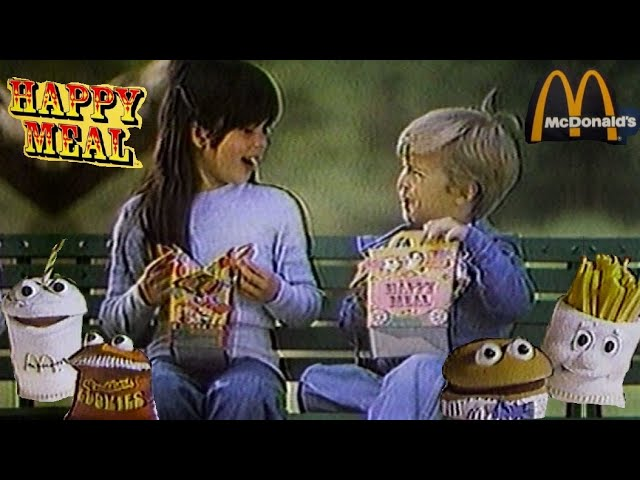 Two smiling children hold Happy Meal boxes alongside animated food characters and McDonald’s branding.